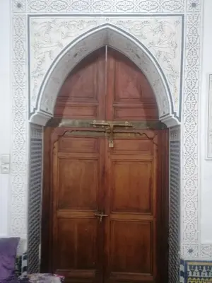 a large wooden door in an archway in a room at Dar lmallouki in Meknès