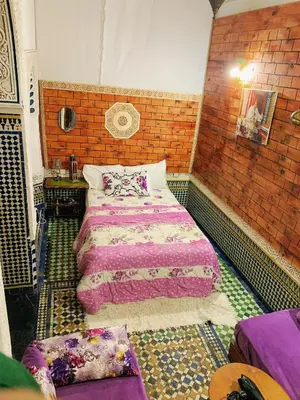 a bedroom with a bed and a brick wall at Dar lmallouki in Meknès
