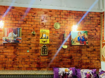 a brick wall with paintings and pictures on it at Dar lmallouki in Meknès