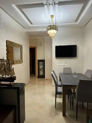 a dining room with a table and a television on the wall at Appartement de luxe in Fès