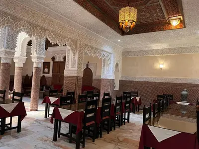 a dining room with tables and chairs and a chandelier at Riad Ritaj in Meknès