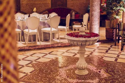 a room with a table and chairs and a fountain at Riad Ritaj in Meknès