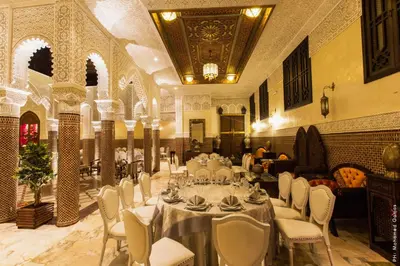 a banquet hall with white tables and white chairs at Riad Ritaj in Meknès