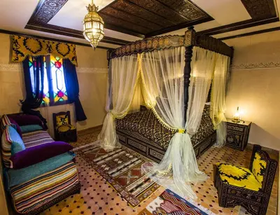a bedroom with a canopy bed with curtains and a chair at Riad Ritaj in Meknès