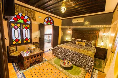 a bedroom with a bed and stained glass windows at Riad Ritaj in Meknès