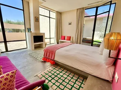 a bedroom with a large bed and large windows at Palais Akbal in Marrakech