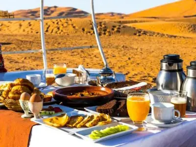 a table with food and drinks in the desert at Awesome Luxury Camp in Merzouga