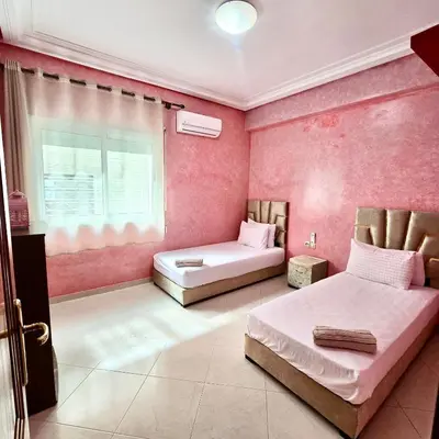 a pink bedroom with two beds and a window at Appartement centre-ville avec Wifi fibre optique in Fès
