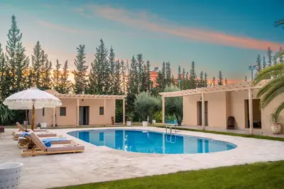 a pool with chairs and an umbrella next to a house at Palais Aureola Luxury Padel and Home Cinema in NʼChaba