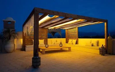 a pergola with a bench on a patio at night at Palais Aureola Luxury Padel and Home Cinema in NʼChaba