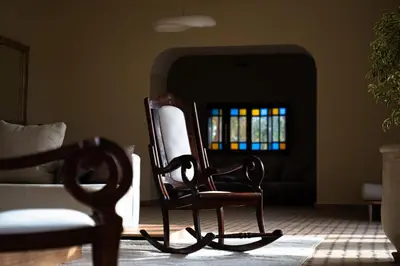 a rocking chair in a living room with a window at Palais Aureola Luxury Padel and Home Cinema in NʼChaba