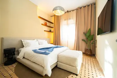 a bedroom with a bed and a chair and a television at Palais Aureola Luxury Padel and Home Cinema in NʼChaba