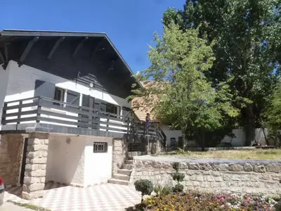 a white house with a balcony and a stone wall at Chalet Authentique Au Centre-Ville in Ifrane