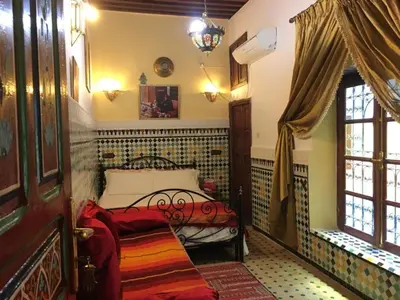 a bedroom with a bed in the corner of a room at Dar Fès Huda in Fès