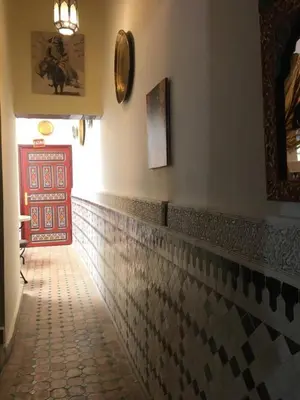 a hallway with a red door and a tile floor at Dar Fès Huda in Fès