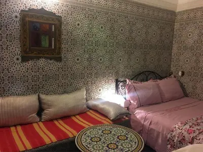 a bedroom with two beds and a table and a mirror at Dar Fès Huda in Fès