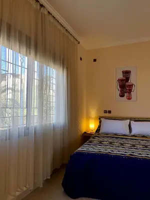 a bedroom with a bed and a large window at Dyafat Abla in Ouarzazate