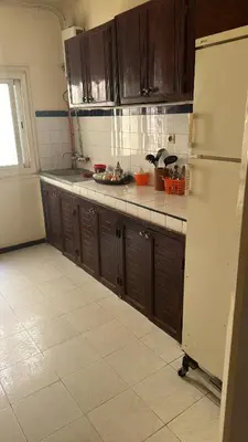 a kitchen with wooden cabinets and a refrigerator at Appartement Sérénité in Khemisset