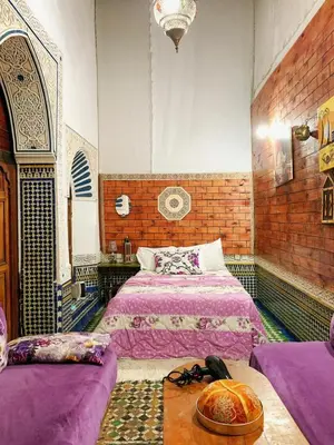 a bedroom with two beds and a table in it at Dar lmallouki 1 in Fès