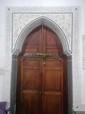 a wooden door with an arch in a room at Dar lmallouki 1 in Fès
