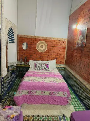 a bedroom with a large bed in a brick wall at Dar lmallouki 1 in Fès