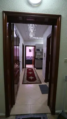 a hallway with a door open to a kitchen with rugs at appartement amira ifrane in Ifrane