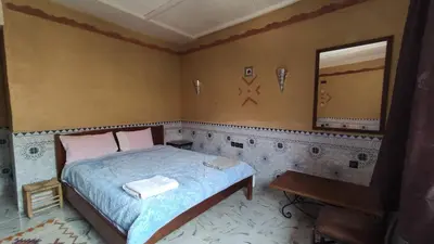a bedroom with a bed and a mirror and a table at Riad La Fleur in Aït Baha