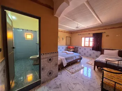 a bedroom with a bed and a bathroom with a shower at Riad La Fleur in Aït Baha