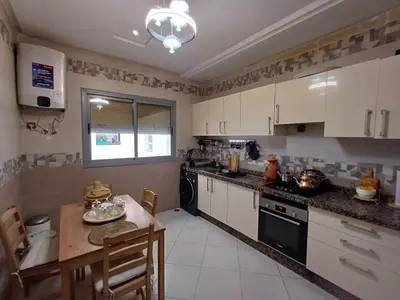 a kitchen with white cabinets and a small table and a tableablish at Belle vacances dans mon App in Meknès