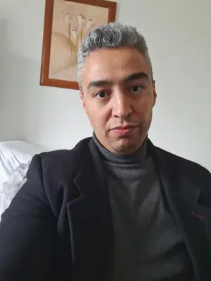 a man in a black suit sitting in a room at Belle vacances dans mon App in Meknès