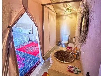 a room with a tent with a bed and a sink at Serenity Sky Luxury Camp in Merzouga