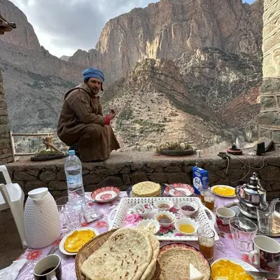 a man sitting in front of a table with food at Gite Itran Taghia in Taghia