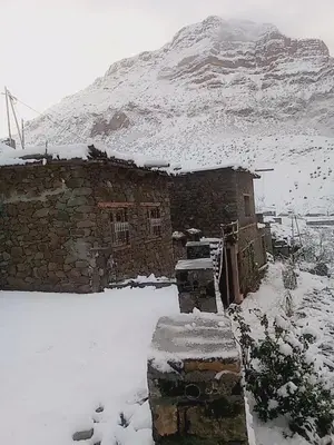 a stone building in the snow with a mountain in the background at Gite Itran Taghia in Taghia