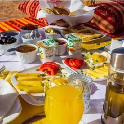 a table topped with plates of food and drinks at Sania Luxury Camp in Merzouga