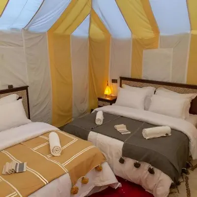 two beds in a room with a tent at Sania Luxury Camp in Merzouga