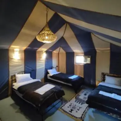 a large room with two beds and a chandelier at Sania Luxury Camp in Merzouga