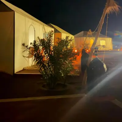 a person standing next to a building at night at Sania Luxury Camp in Merzouga