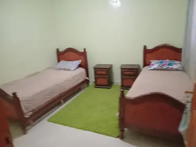 a room with two beds and a green rug at Billa appart in Midelt