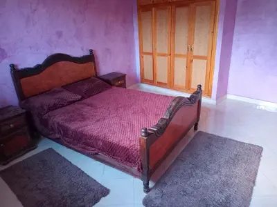 a bedroom with a bed and two rugs in it at Billa appart in Midelt