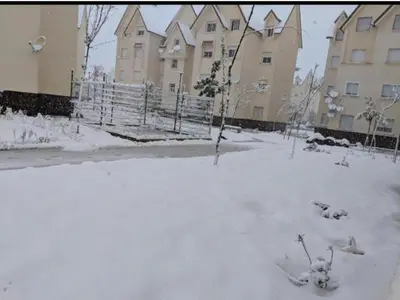 a yard covered in snow in front of a building at Casa De La Mama chauffée cosy et climatisée 3 pièces Ifrane sous la neige in Ifrane
