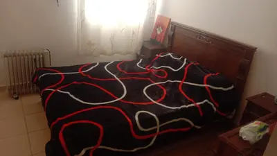 a bed with a black and red blanket on it at Vue Neige et Forêt Ifrane bien au chaud 3 pieces in Ifrane