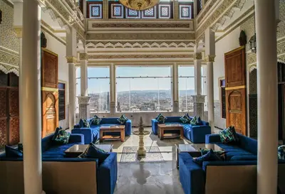 a living room with blue couches and a large window at Riad Zaya Fes in Fès