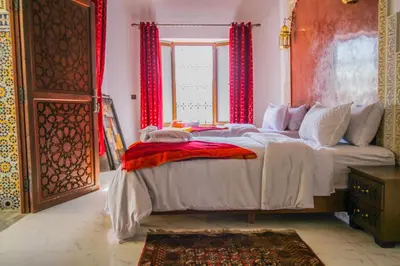 a bedroom with a large bed with red curtains at Riad Zaya Fes in Fès