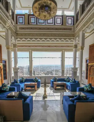 a large living room with blue couches and a chandelier at Riad Zaya Fes in Fès