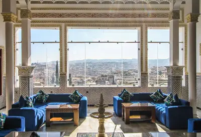 a living room with blue couches and large windows at Riad Zaya Fes in Fès