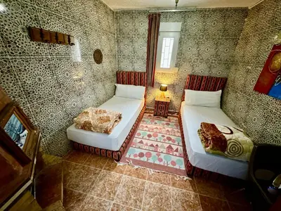 a small room with two beds and a lamp at Auberge Sous Les Étoiles Lac Ouiouane in Kasba des Aït Athmane