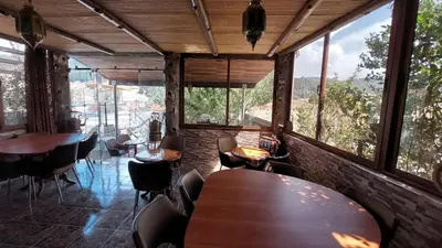 a restaurant with tables and chairs and large windows at Auberge Sous Les Étoiles Lac Ouiouane in Kasba des Aït Athmane