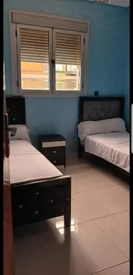 two beds in a room with blue walls and windows at Villa Sarghini in Sidi Bouzguia