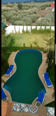 a swimming pool with two lounge chairs and a swimming poolvisor at Villa Sarghini in Sidi Bouzguia