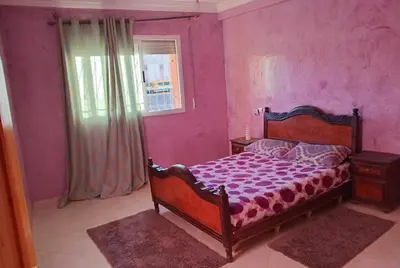 a bedroom with a bed with purple walls and a window at Billa appart in Midelt